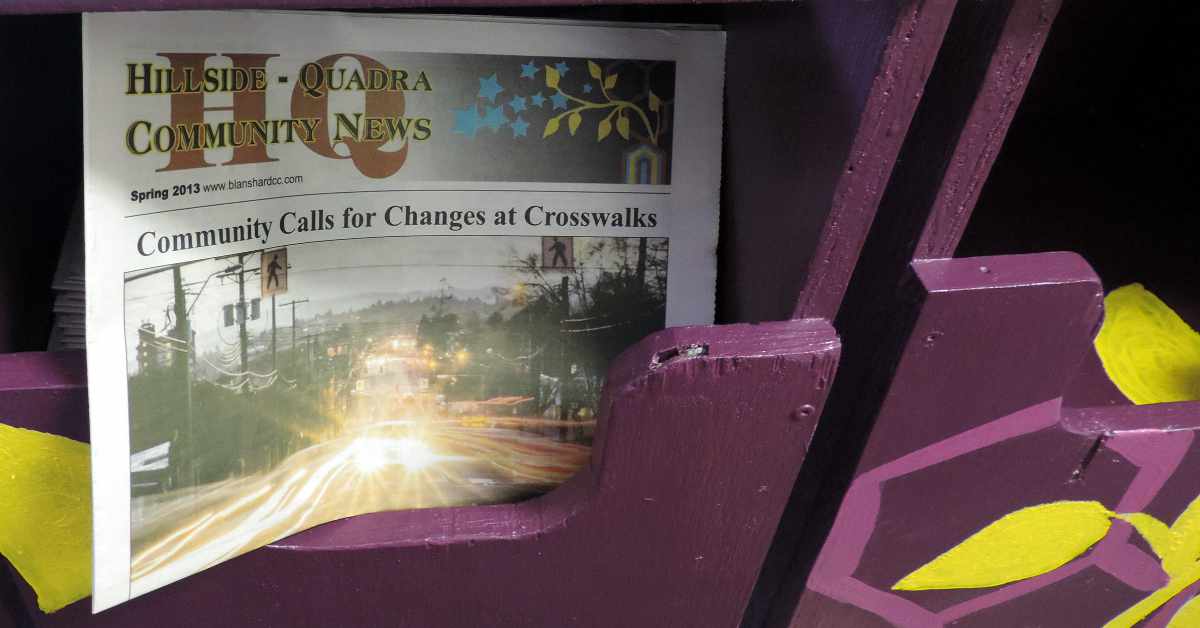 The cover of a 2013 issue of Hillside Quadra Community News displayed in a neighbourhood newspaper drop box.