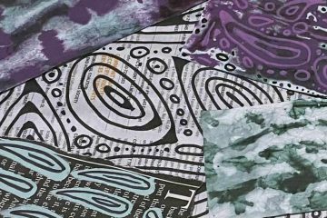 The image shows a collage of various textured and patterned papers layered together. Some papers feature abstract designs drawn over printed text from book or newspaper pages, such as black and white swirling lines or blue teardrop shapes. Others have tie-dye or marbled patterns in colors like green, purple, and blue. The overall composition is artistic and eclectic, combining text, patterns, and color in a mixed-media style.