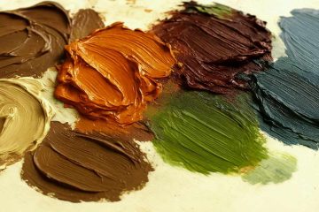 A close-up photo of thick, textured blobs of oil paint in earthy and autumn-inspired tones arranged on a light-colored palette. The colors closely resemble the October 2025 palette, including dark brown, burnt orange, burgundy, beige, green, and blue-gray hues, with visible brush strokes adding texture and depth.